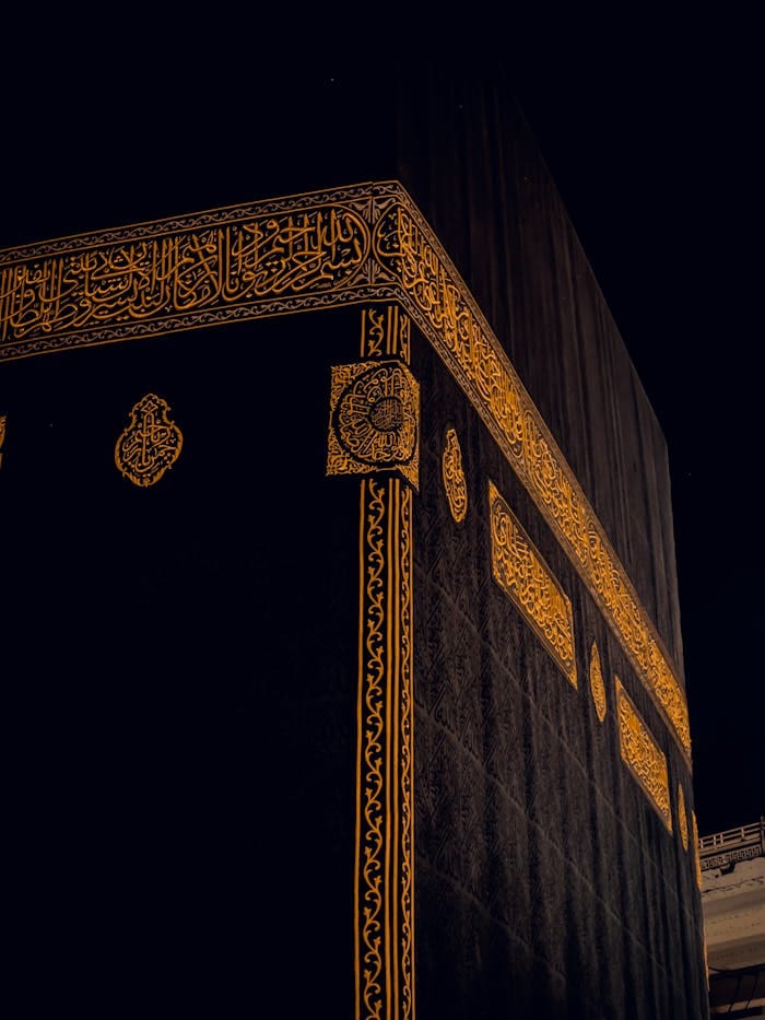 Close-up of the Kaaba in Mecca, Saudi Arabia, showing intricate golden patterns at night.