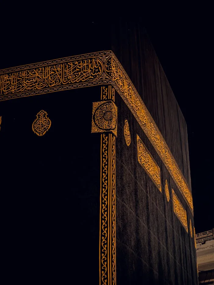 Close-up of the Kaaba in Mecca, Saudi Arabia, showing intricate golden patterns at night.
