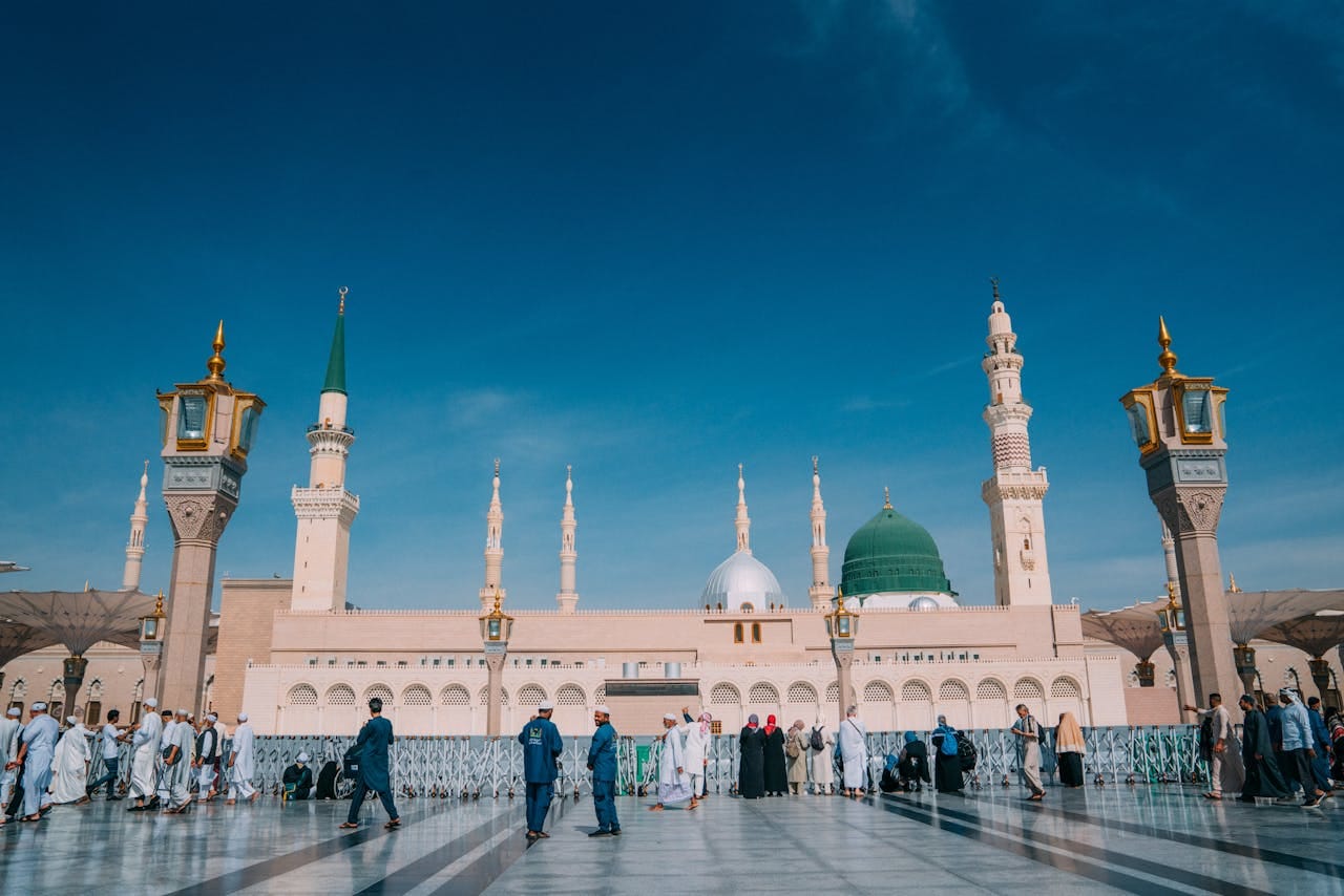 Captivating image of the Prophet's Mosque with visitors under a clear blue sky in Medina.